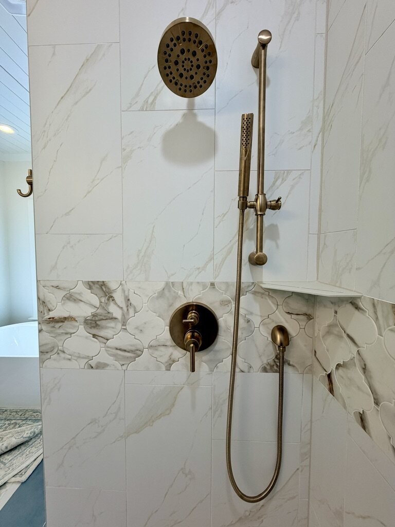 Marble-look tile shower with brass fixtures