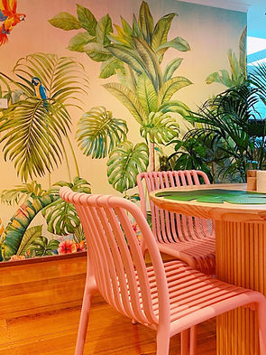 Gorgeous pink dining chairs, round wood dining table, with a jungle wallpaper background