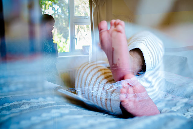Multi exposure photograph of mother rand newborn baby lying on bed in home photography