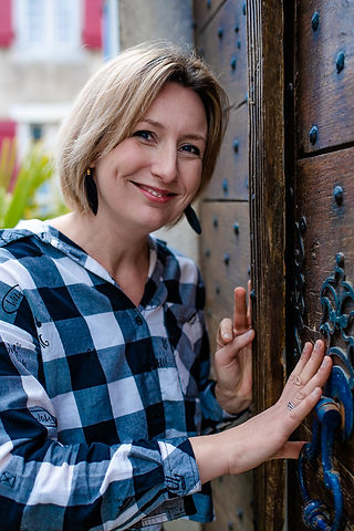 Portrait of a woman smiling at camera leaving against a old house door in SALIES DE BEARN 