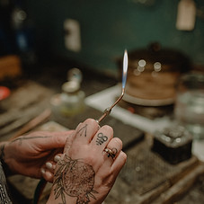 Hands holding a soldering torch over a workbench