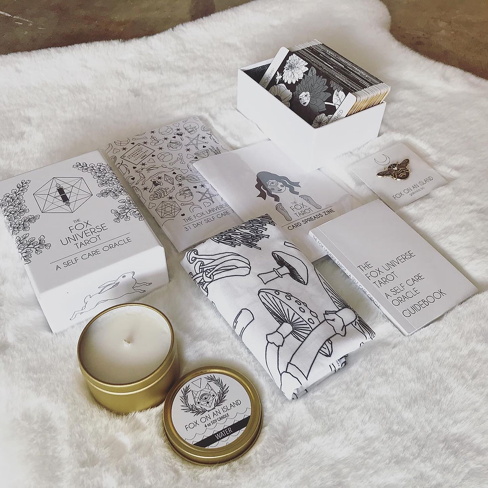 Thumbnail: An image of a collection of products including a package of tarot cards, an enamel pin on a backing card, a golden round tin with candle inside, two printed booklets and a black and white printed cloth