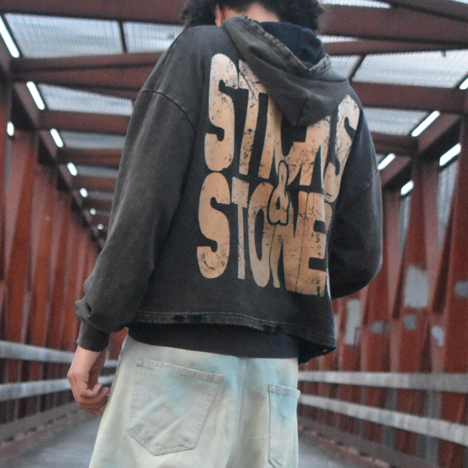A dark brown cropped vintage style hoodie pictured from the back with text reading "Sticks and stones"
