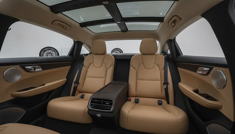 Tan leather rear car interior with panoramic glass roof, dual back seats, and speaker doors; empty, sleek showroom feel.