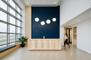 Double-height reception area in Cambridge with navy feature wall, timber desk and globe pendant lighting.