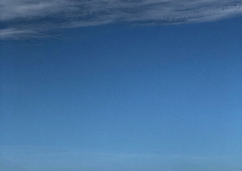 Un barco varada en la orilla bajo un cielo azul con nubes dispersas.