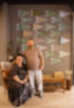 Couple posing by a wall of triangular camp pennants.