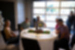 Group of people smiling at a table during a past event.