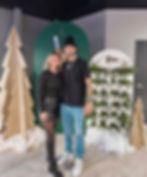 Couple posing at a winter-themed past event with trees.