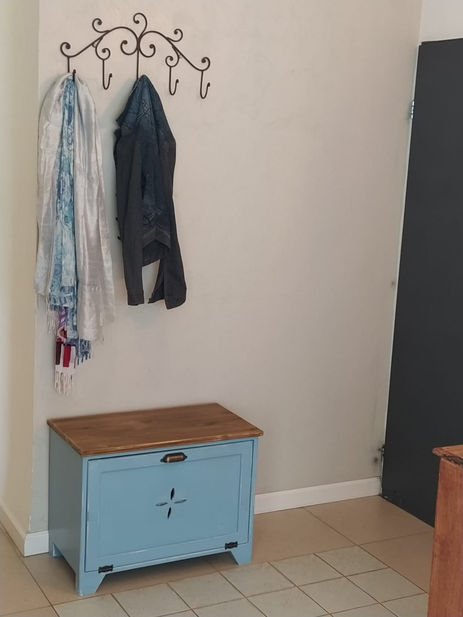 ספסל כניסה קטן מעץ מלא עם תא אחסון לנעליים.