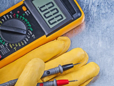 Digital multimeter, electrical testing probes and protective gloves representing electrical engineering, maintenance and testing activities.