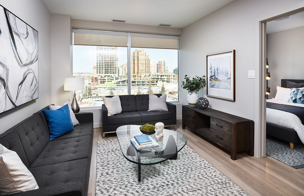 Modern one-bedroom apartment at Cube Apartments in Calgary's Beltline featuring an open-concept living room, large windows with downtown Calgary views, contemporary furnishings, natural light, spacious layout, and modern finishes. Rental suite located in the heart of the Beltline near 17th Avenue SW, ideal for renters searching for living in Beltline Calgary, Beltline Calgary apartments, downtown Calgary rentals, walkable Calgary apartments, one-bedroom apartments Calgary, and modern Calgary rental communities.