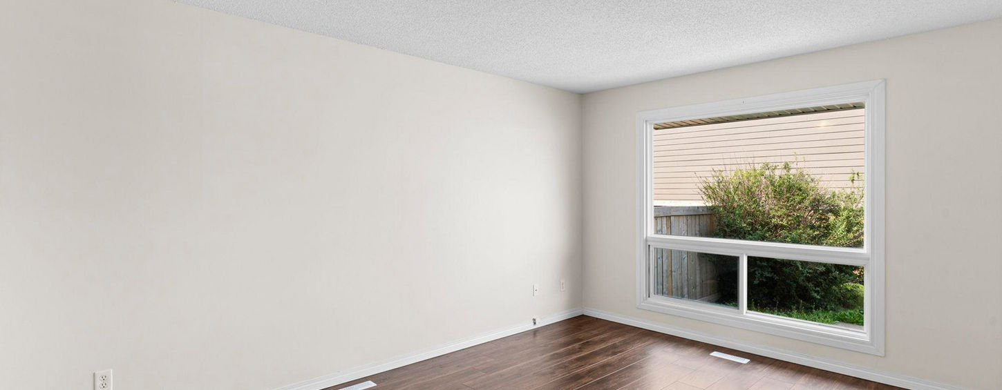 Bedroom with large window and wood flooring.