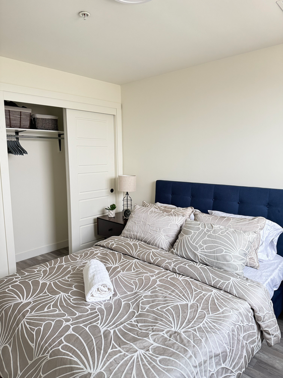 Compact and comfortable bedroom with soft textiles, layered pillows, and bright natural light.