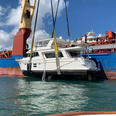 Motor yacht lifted in crane slings to load onto a cargo ship