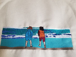 Embroidery of two kids looking at ocean waves.