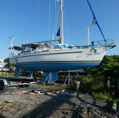 White sailboat hauled out on jack stands in a Florida boatyard for a hull inspection