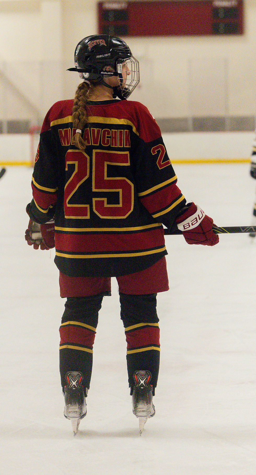 Back of a Female hockey player holding a stick