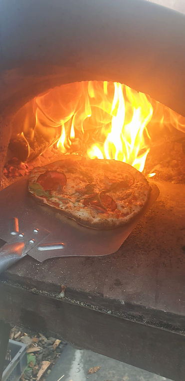 Pizza baking in a wood-fired oven at a farm camp.