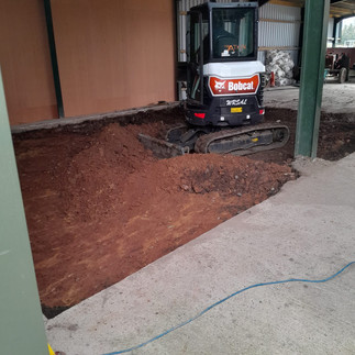 digging out a concrete floor with mini digger to expose the earth below