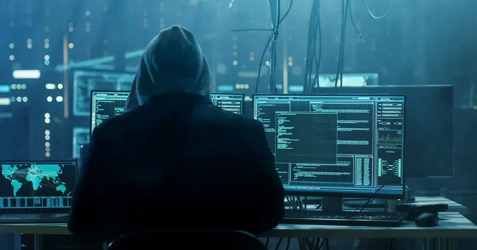 A man who appears to be a hacker sitting in room full of computers.