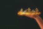 Woman's hand holding a burning crown over black background.jpg