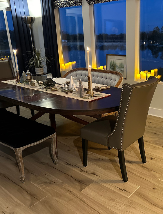 Black wooden table with different style chairs around it and table decorations in the middle of table