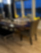 Black wooden table with different style chairs around it and table decorations in the middle of table