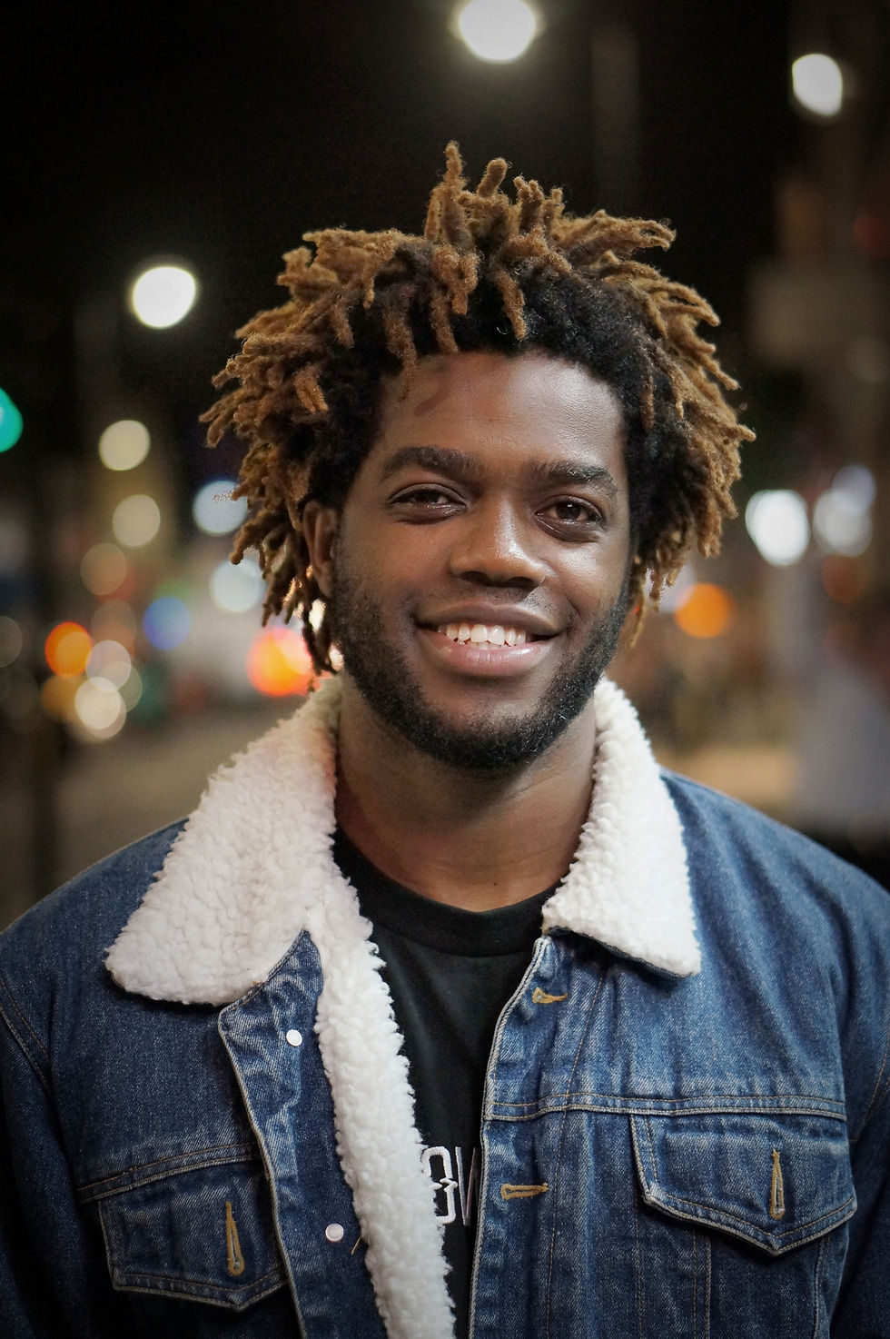 Smiling man with dreadlocks, night cityscape