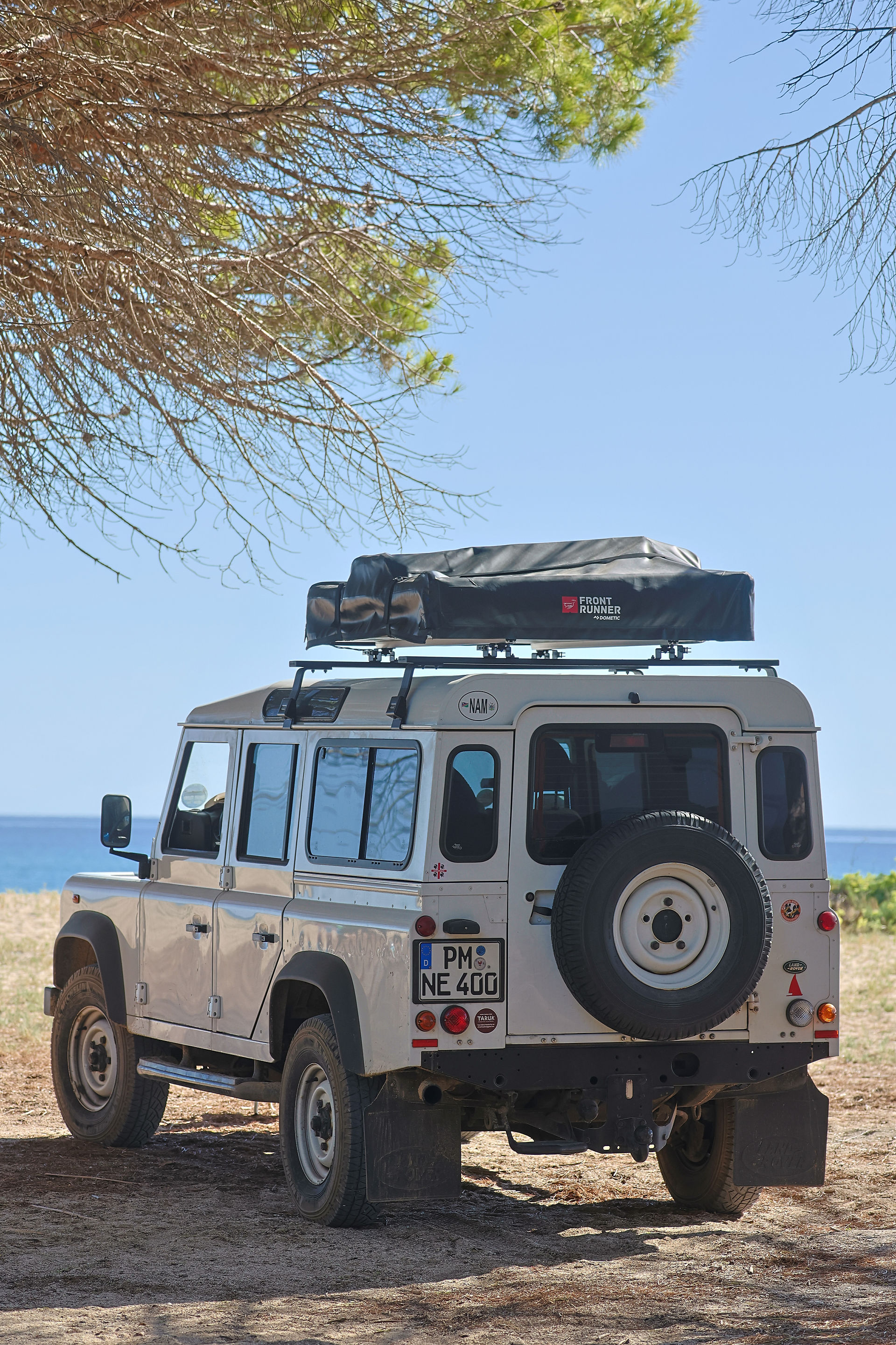 Land Rover Defender steht mit Dachzelt am Strand in Sardinien