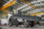 Truckrite's workshop showing a tipper truck with its tray lifted by a yellow overhead crane, undergoing mechanical servicing