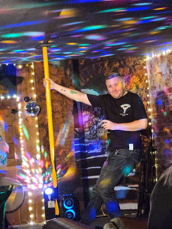 Queer and Now member holding onto a pole with a drink in one hand