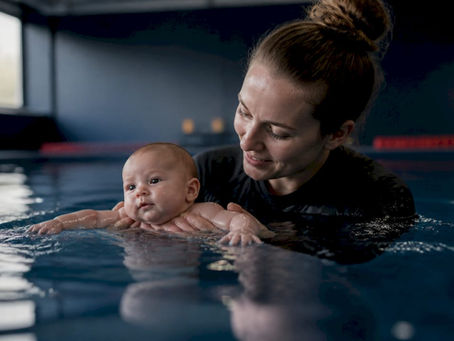 Instructor supporting infant mid-water flotation in pool