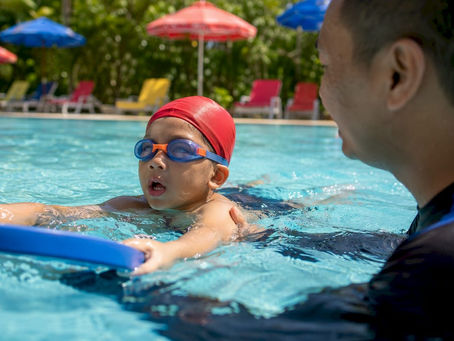Young child practicing swim kicks with instructor support