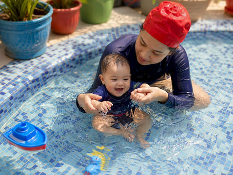Mother guiding infant in swim lesson pool