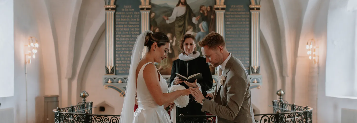 Bride and groom exchanging rings during church wedding in Denmark