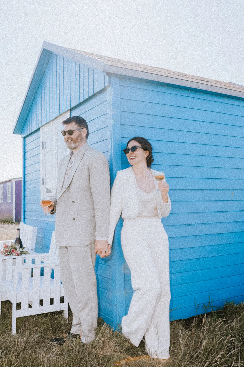 Ærø elopement with champagne, rings and bouquet by a blue beach hut near the sea.