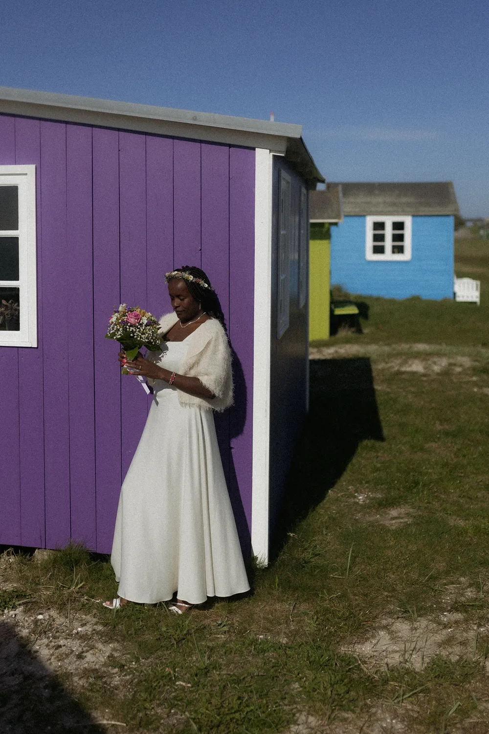 Bride standing beside colourful beach huts at Vesterstrand on Ærø.