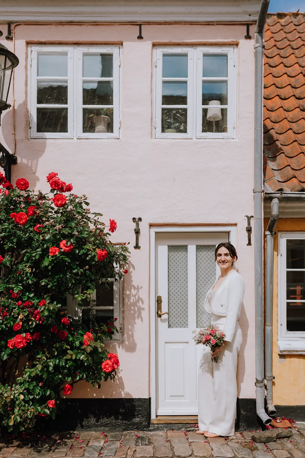 Bridal portrait in Ærøskøbing beside a blue door and colourful historic houses.