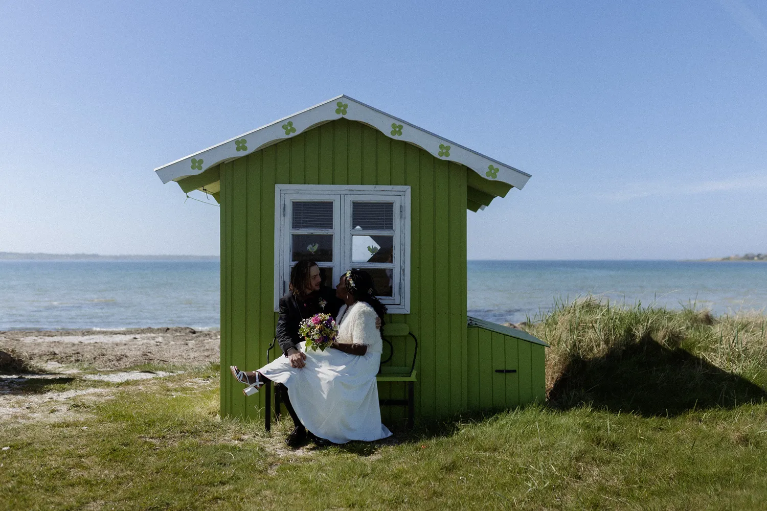 Couple kissing beside colourful beach huts on Ærø during spring wedding portraits.