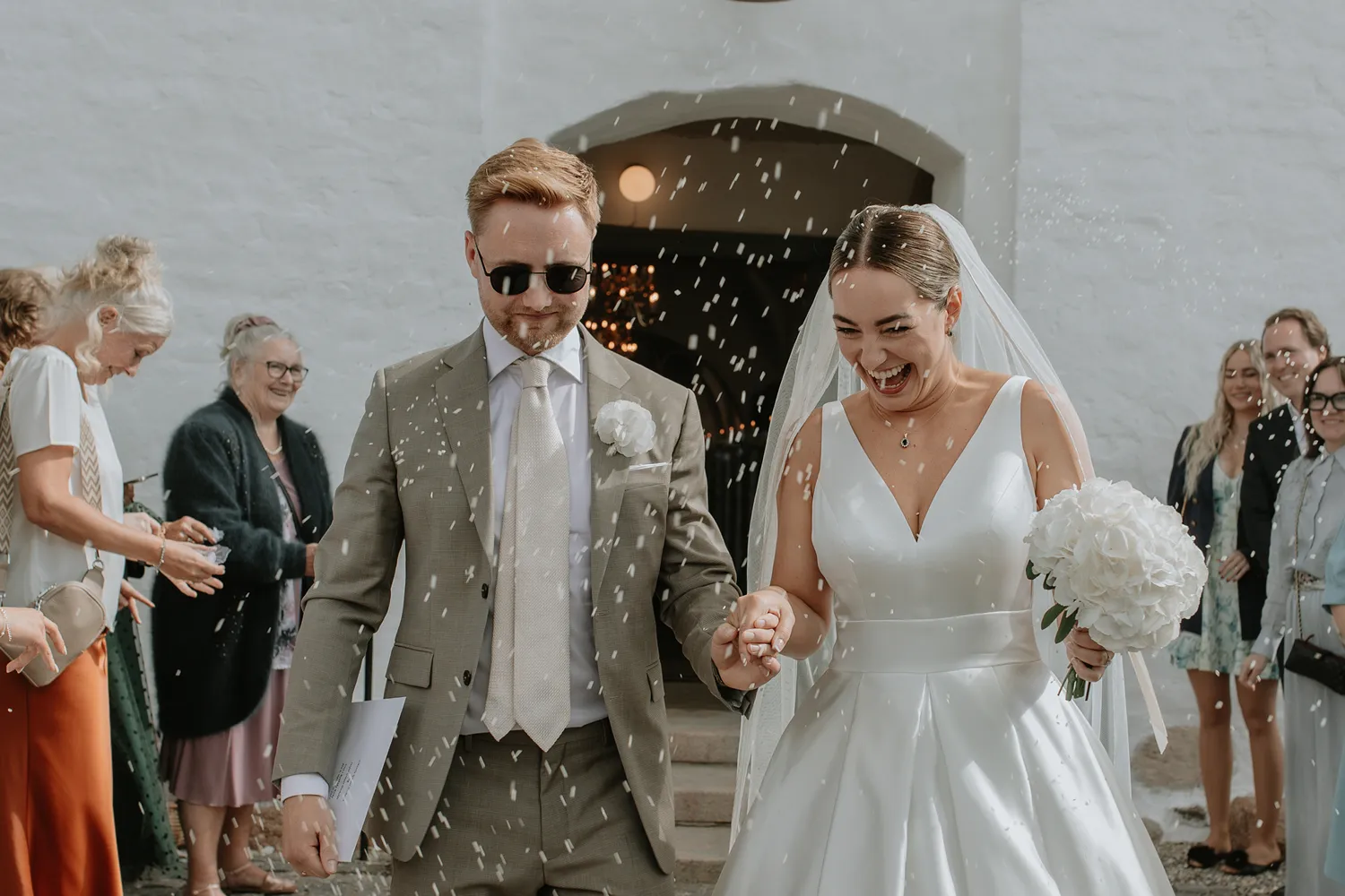 Joyful confetti moment outside church during Holckenhavn wedding