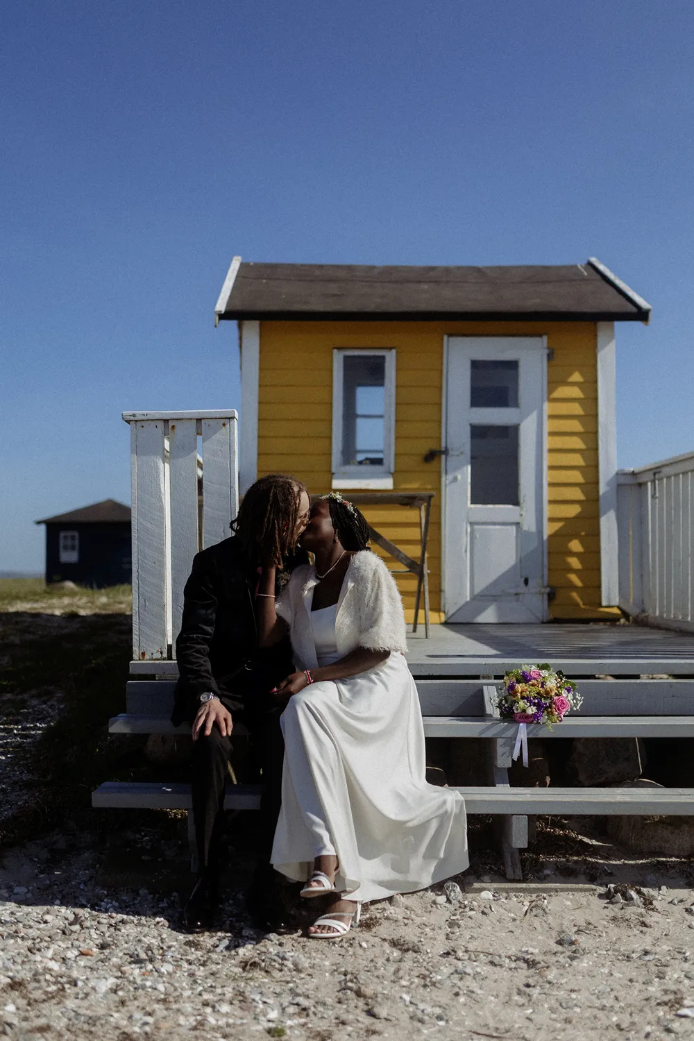 Couple portrait beside yellow beach hut on Ærø island.
