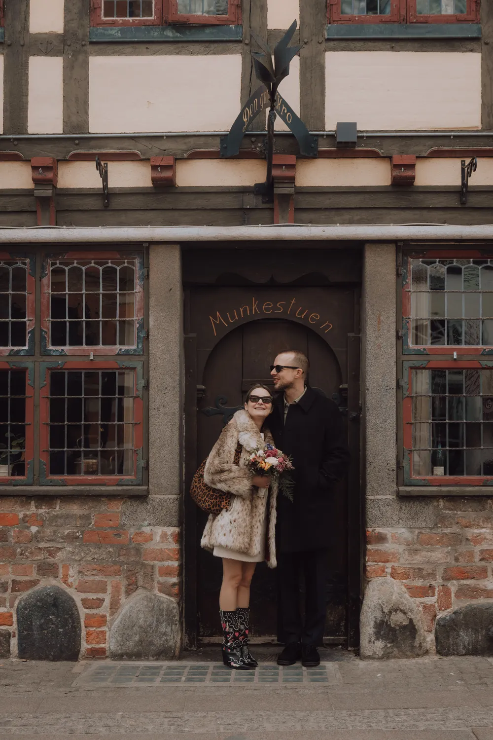 Stylish couple portraits with cowboy boots and spring bouquet in Odense.