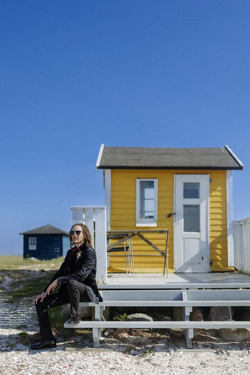 groom portrait beside yellow beach hut on Ærø island.