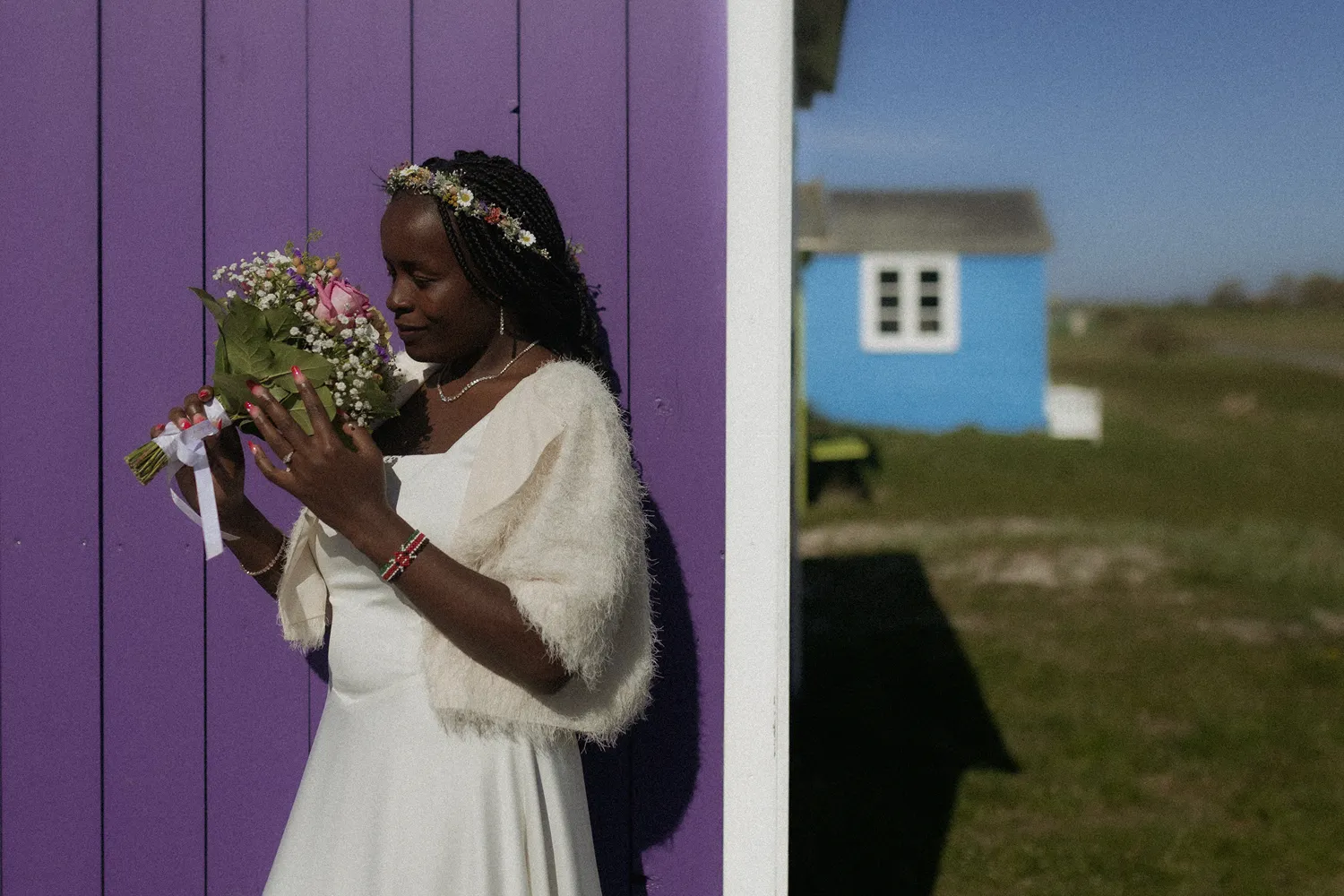 Bride standing beside a green beach hut during intimate wedding on Ærø island in Denmark.