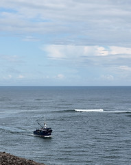 A distance shot of a fishing boat coming in at Winchester Bay