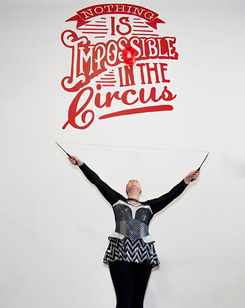A young female circus performer poses under a large sign that reads Nothing is Impossible in the circus