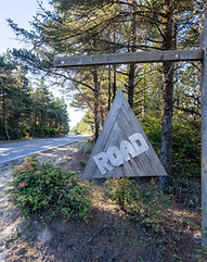 A wooden sign, it has a hanging wooden triangle with the word road on it at triangle road campsite