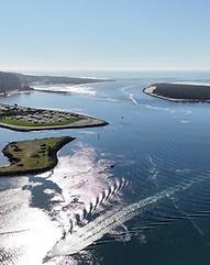 An aerial view of blue water, green forests and campsites in WInchester Bay