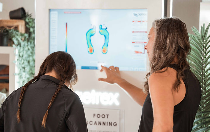A female wild coast running team members points at the foot scanning machine for a shoe fitting